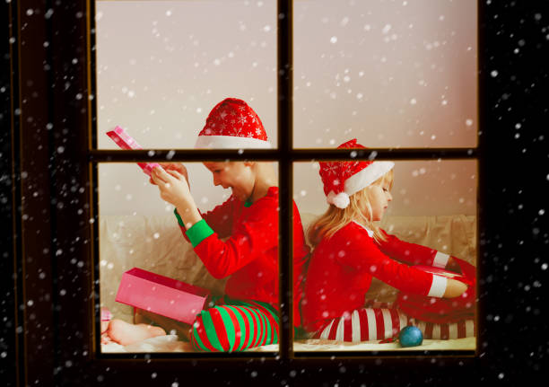 istock Kids opening christmas presents at home from outside window 882984324