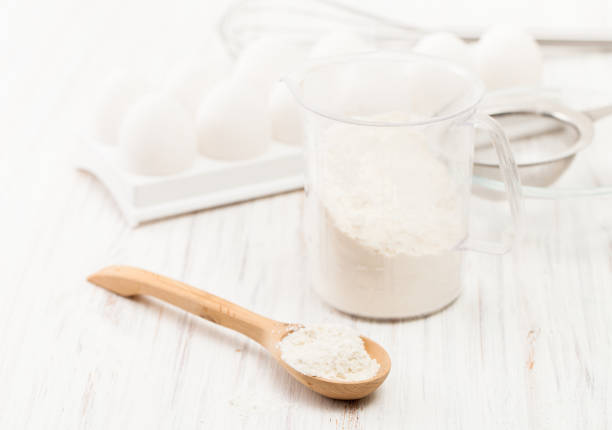 istock Flour in a wooden spoon on a white table in the kitchen 882984740