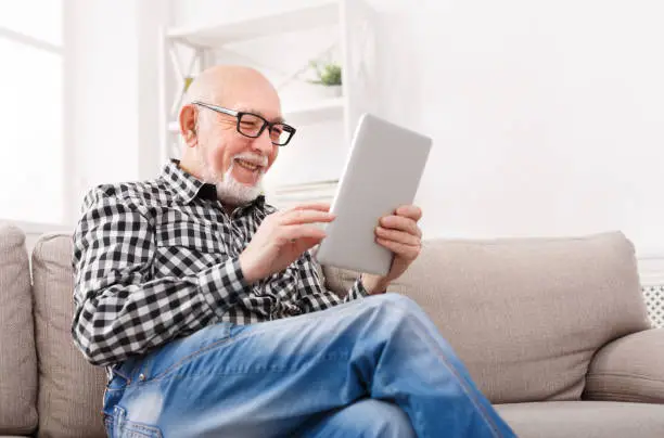 Photo of Senior man reading news on digital tablet