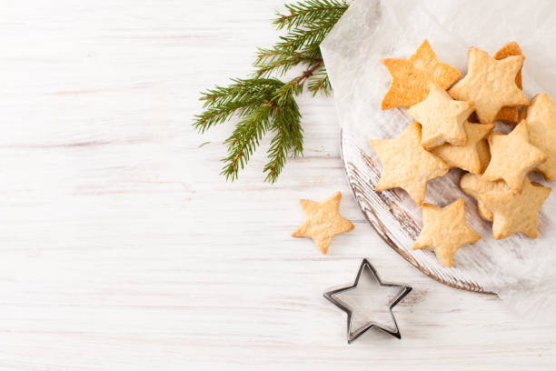 fresh baked biscuits on the baking paper with fir branch on white - cookie christmas shortbread food imagens e fotografias de stock