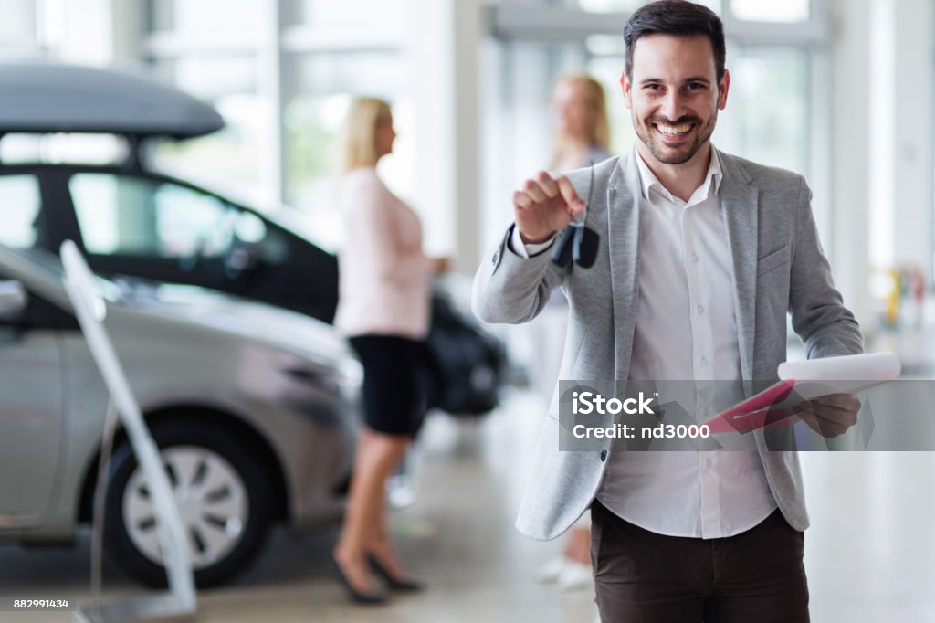 Handsome salesman at car dealership selling vehichles Handsome young salesman at car dealership selling vehichles Car Stock Photo