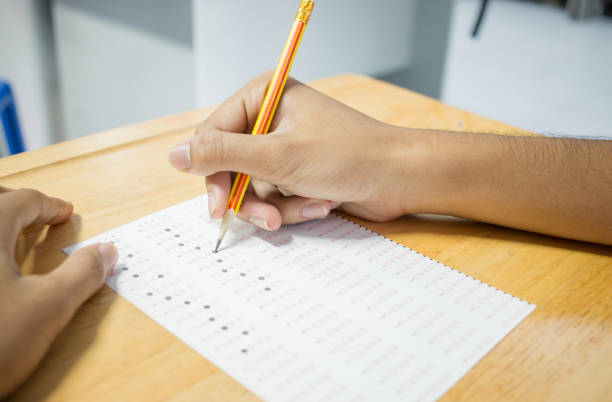 istock Top view of School Asian students taking exams writing answer optical form with pencil in university classroom, view of having exams in class on seat rows, Education test and literacy concept. 882998914