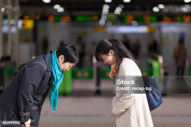 Two Japanese Businesswomen Bowing To Each Other At Station Stock Photo - Download Image Now