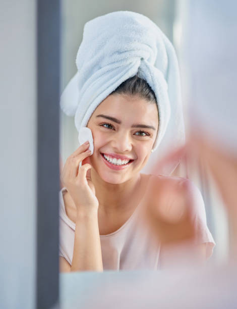 She enjoys looking after her skin Cropped shot of a beautiful young woman exfoliating her skin in the bathroom at home facial cleanser stock pictures, royalty-free photos & images