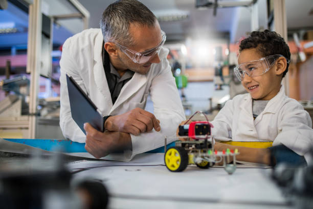 istock Happy teacher talking to small black boy in laboratory. 883020116