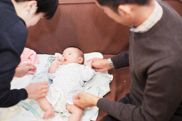 istock father and mother dressing their newborn baby 883020202
