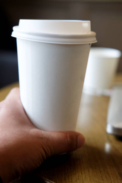 istock White disposable paper cup with plastic lid in young hand man 883041986