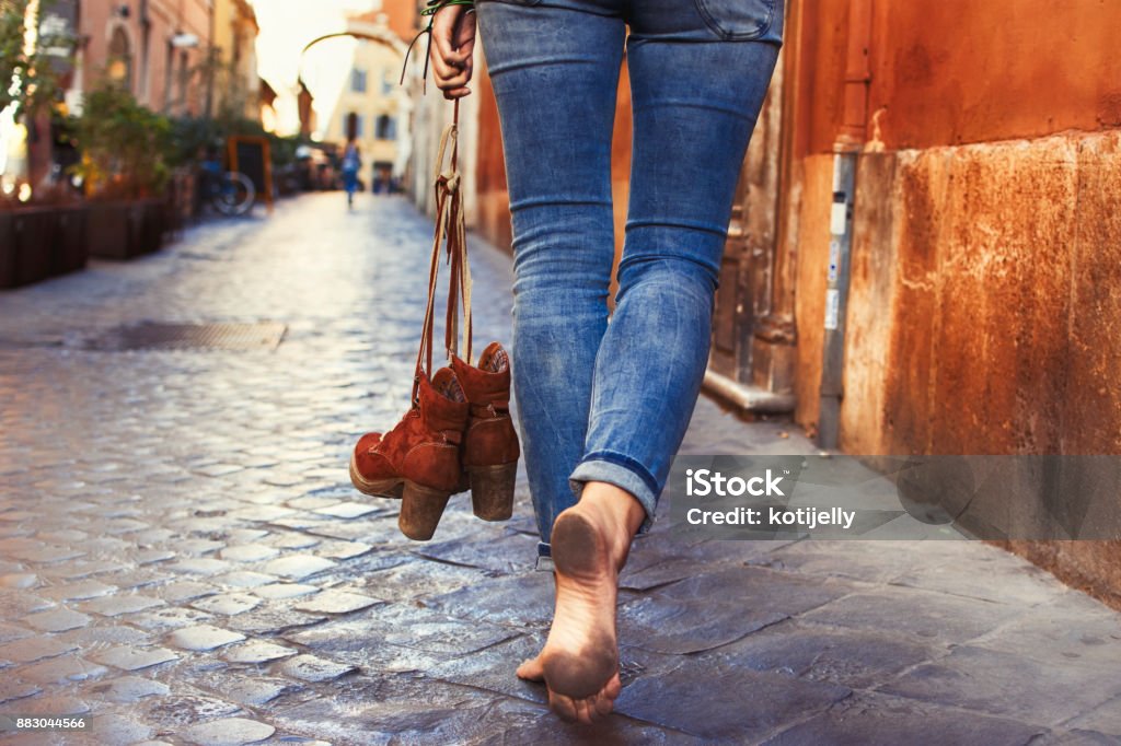 Barefoot woman walking on street Barefoot woman walking on street of Rome Barefoot Stock Photo