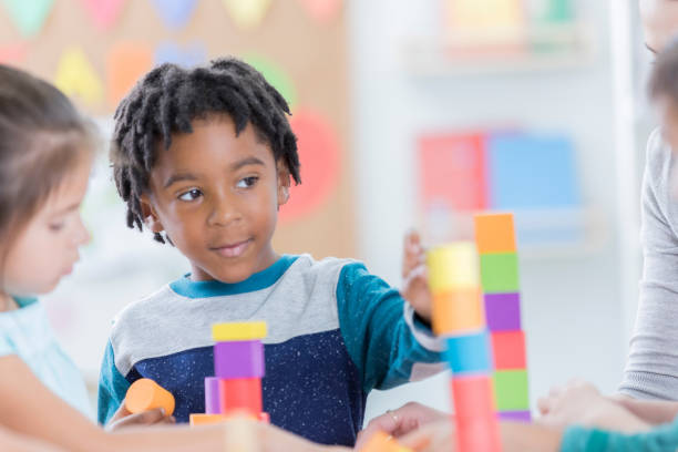 istock Little boy enjoys playing with building blocks at school 883044642