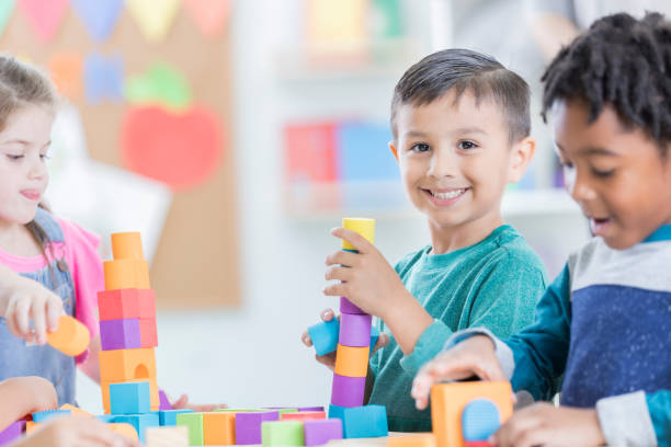 istock Little boy smiles for camera during kindergarten play time 883044652