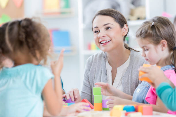 attento insegnante d'asilo si siede con gli studenti - block togetherness happiness indoors foto e immagini stock