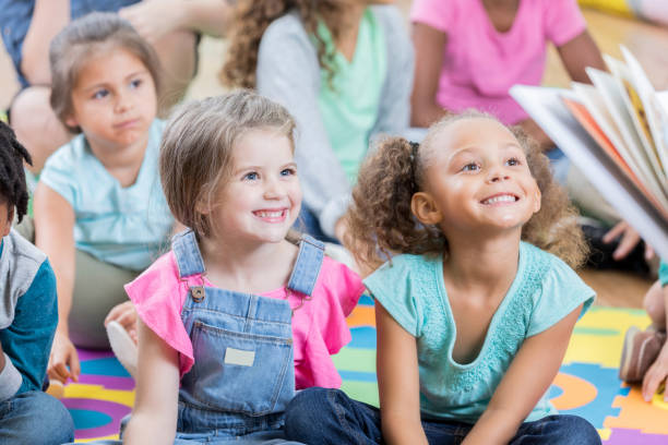 istock Little girls enjoy story time during after school program 883044668