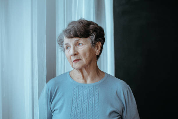 Worried grandmother with alzheimer Worried grandmother with alzheimer isolated looking through window in nursing house one senior woman only stock pictures, royalty-free photos & images