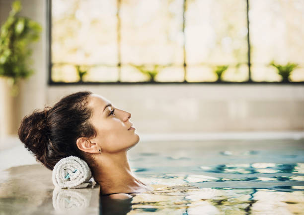 mujer hermosa sana relajante en el spa piscina - balneario fotografías e imágenes de stock