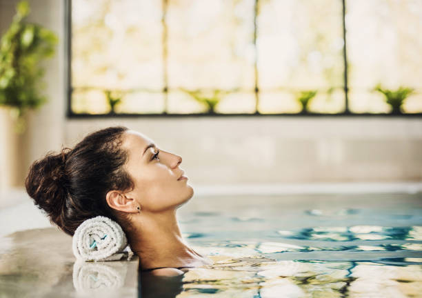bella donna sana che si rilassa nella piscina termale - trattamento di benessere foto e immagini stock