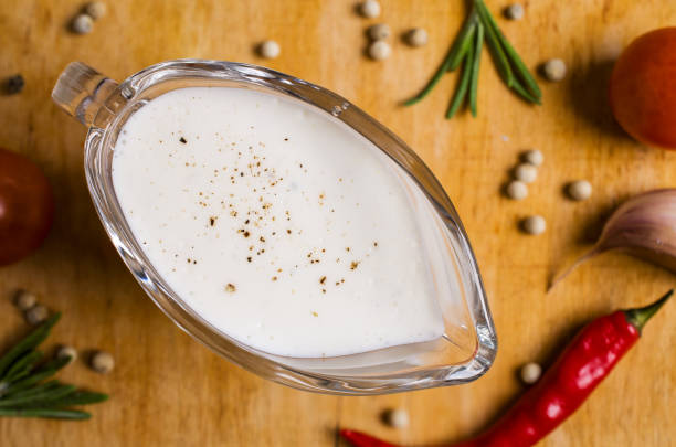 White sauce in a gravy boat on a wooden background. Selective focus.