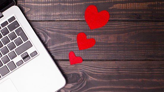 A heart connected with computers. Hearts on the wooden background.