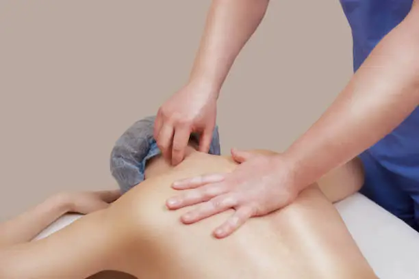 Photo of The masseur makes a massage on the back of the patient in the beauty salon.