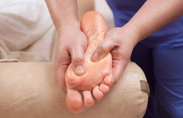 le médecin-podiatre fait un examen et de massage du pied du patient - reflexology pedicure massaging human foot photos et images de collection