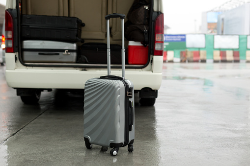 Luggage stand on the road and arrange on the van for a trip in rainy day