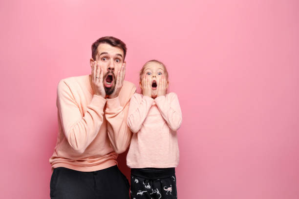 istock Surprised young family looking at camera on pink 883092634