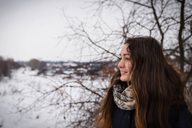 Pensive and romantic girl with beautiful long hair on the winter background looking away on the winter landscape