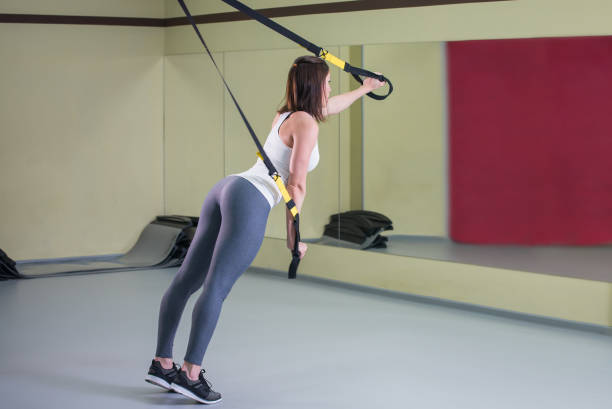 young woman doing suspension training push-ups with trx fitness straps, side view - body building determination deltoid wellbeing imagens e fotografias de stock