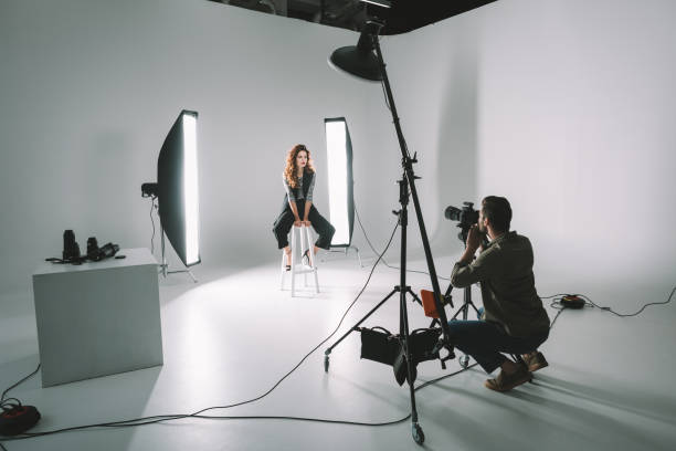 professional fashion shoot professional photographer and beautiful model on fashion shoot in photo studio with lighting equipment photo studio model stock pictures, royalty-free photos & images