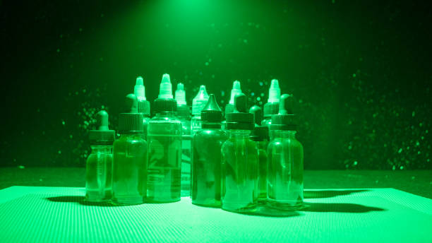 istock Vape concept. Smoke clouds and vape liquid bottles on dark background. Light effects. 883117562