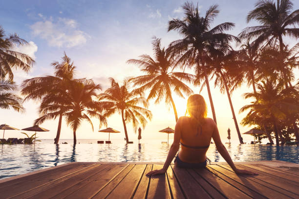 Woman enjoying vacation holidays luxurious beachfront hotel resort swimming pool Woman enjoying vacation holidays at luxurious beachfront hotel resort with swimming pool and tropical lansdcape near the beach caribbean beach sunset stock pictures, royalty-free photos & images