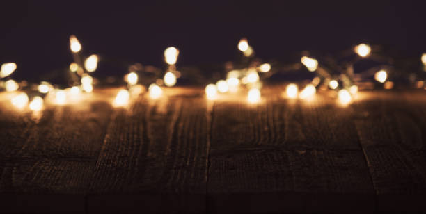 istock Blurred christmas lights on wooden rustic table. Moody christmas background with copyspace 883125300