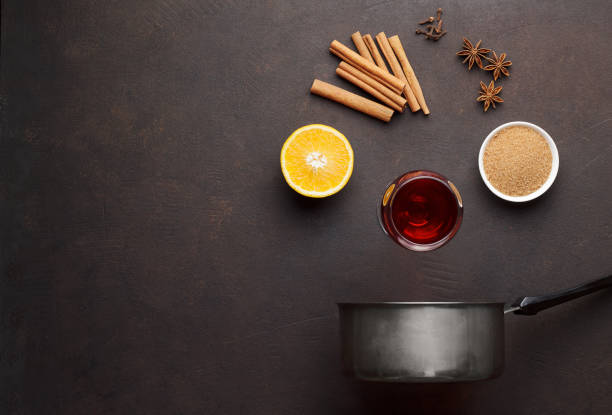 istock Mulled wine ingredients: cinnamon, anise, clove, orange, wine and sugar on brown stone table. 883127864