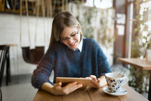 istock Happy young woman drinking coffee and using tablet 883128256