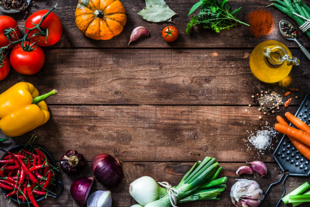 Frame of assorted fresh vegetables on rustic wooden table Top view of a rustic wooden plank with fresh organic vegetables, spices and cooking oil places all around the border making a frame and leaving useful copy space for text and/or logo at the center. DSRL Studio photo taken with Canon EOS 5D Mk II and Canon EF 24-105mm f/4L IS USM Wide Angle Zoom Lens organic spice stock pictures, royalty-free photos & images