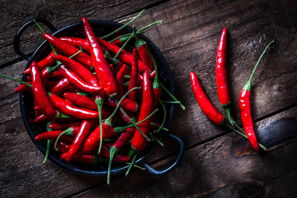 peperoncini rossi sparati dall'alto su un tavolo rustico in legno - red hot foto e immagini stock