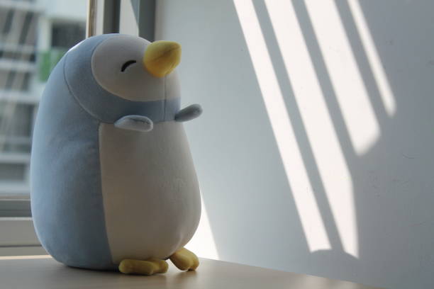 istock Penguin toy sitting by the window in shadows 883139588