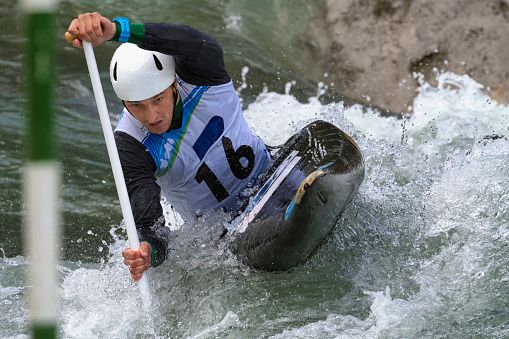 Male canoeist bending and reaching the green gate during the sport race