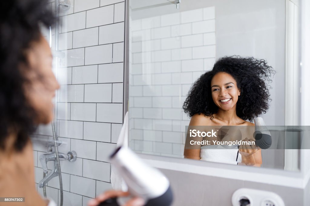 Lächelnde Frau hält eine Haar Trockner, Blick auf Spiegel auf ihren wehenden Haaren - Lizenzfrei Badezimmer Stock-Foto