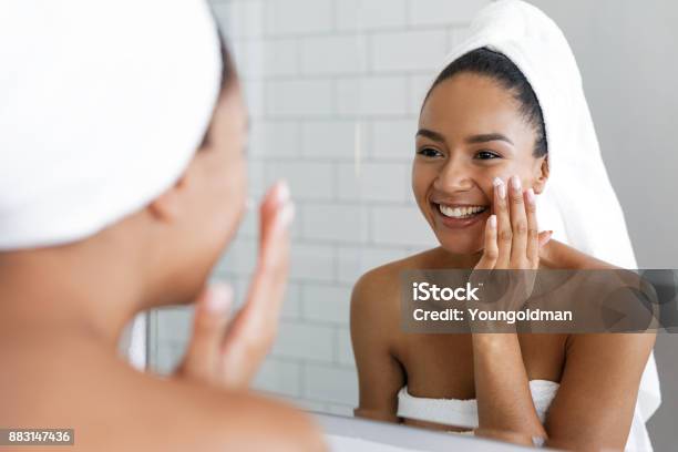 Photo libre de droit de Heureuse Femme Mettant Sur Hydratant Pour Le Visage Avec La Main Dans La Salle De Bain Miroir banque d'images et plus d'images libres de droit de Soin de la peau