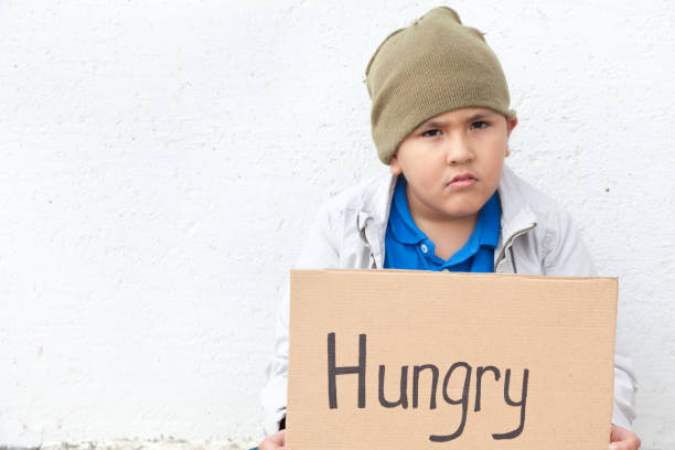 istock Young runaway boy sits outside and begs for food 883147572
