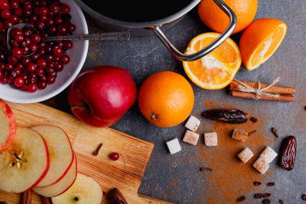 istock On the table, apples and oranges, cranberries, cinnamon sticks, dates and a saucepan. View from above. 883153344