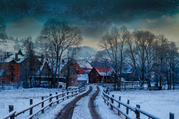 A serene snowy path through tall trees leads to a cozy cabin, perfect for picturesque winter moments