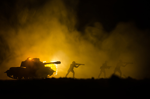 Military silhouettes of soldiers against the backdrop of dark foggy sky Battle scene with explosion and burning clouds behind fighing soldiers.