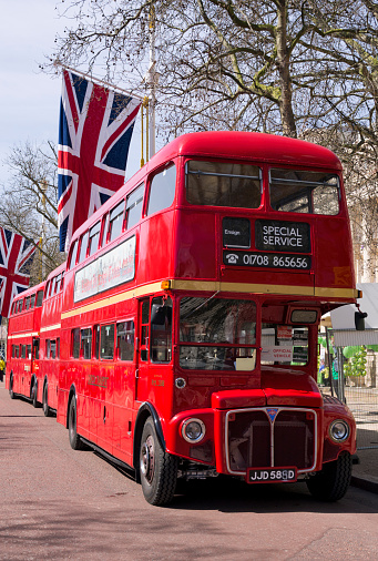 A row of Union flags and red London Routemaster double-decker buses in The Mall, London. They were there as transport during the annual London Marathon.