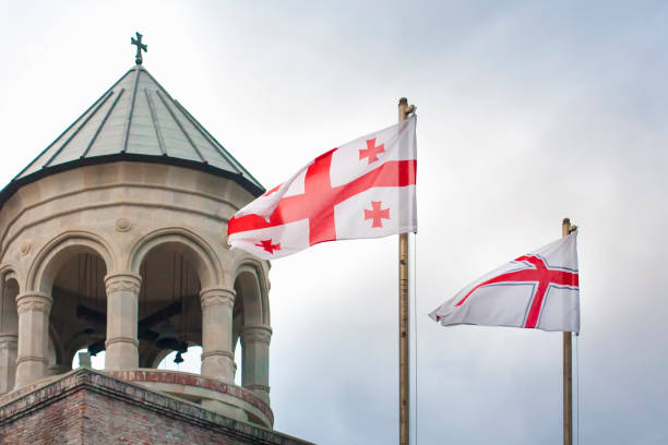Georgia flags with ancient georgian church and sky in background. stock photo