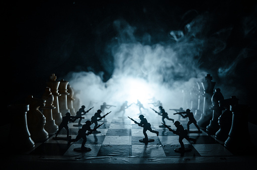 War concept. Silhouettes of soldiers on chessboard. War Concept. Military silhouettes fighting scene on war fog sky background, Chess board game concept of business ideas and competition and strategy