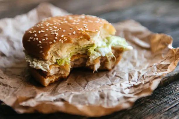 Photo of Bitten hamburger on wooden background