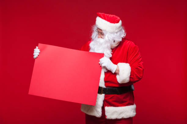 istock Santa Claus pointing in blank advertisement banner isolated on red background with copy space red leaf 883177046