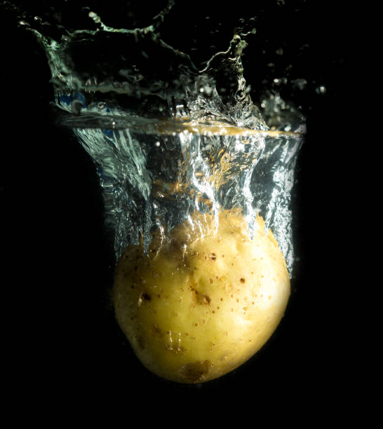 istock potato in water with splashes on a black background 883202962
