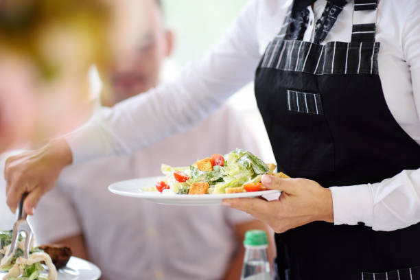 Waiter carrying plates with salad on party or wedding reception